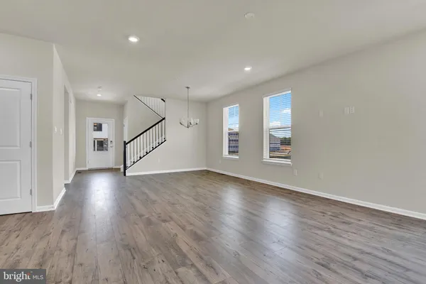 a view of an empty room with wooden floor and stairs