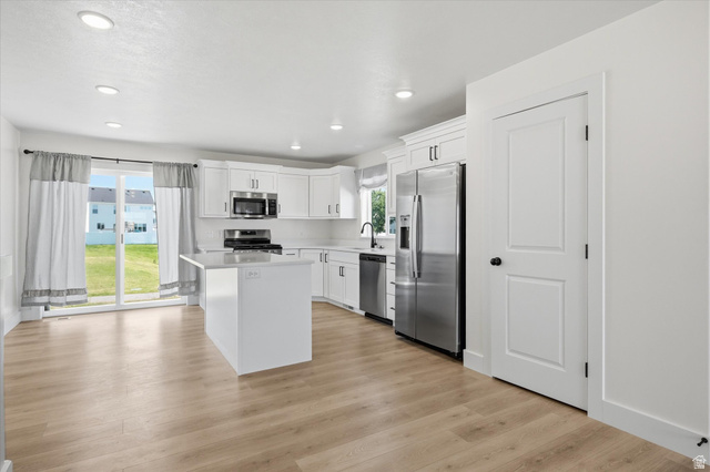 730 West 500 North Smithfield, UT 84335 - Photo 9 of 46 Modern kitchen featuring a white island, stainless steel appliances, recessed lighting, wood-finish flooring, and white cabinetry