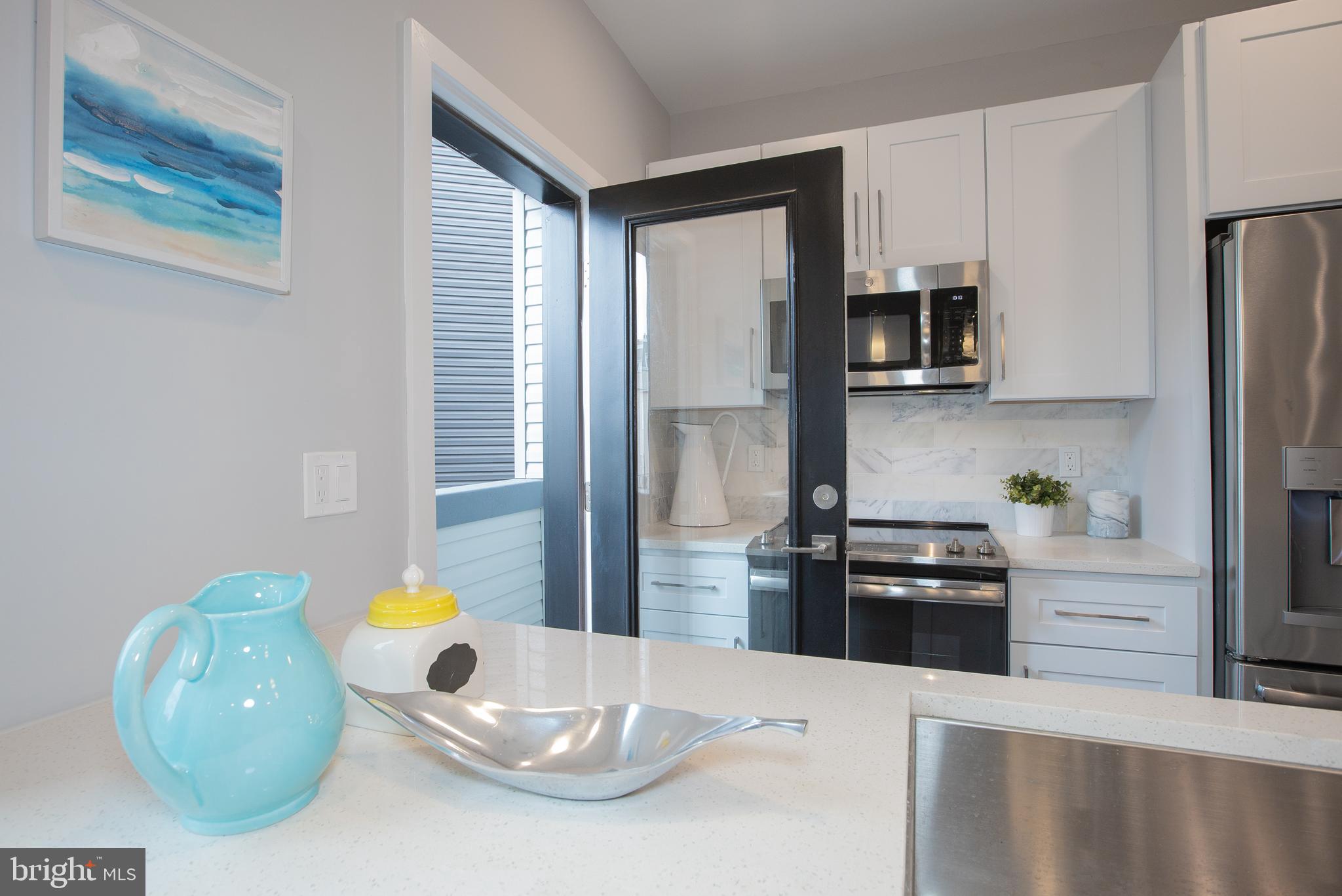 1534 Ridge Avenue, Unit 202 Philadelphia, PA 19130 - Photo 18 of 20 a kitchen with stainless steel appliances kitchen island granite countertop a refrigerator a stove a sink a microwave a dining table and chairs with wooden floor