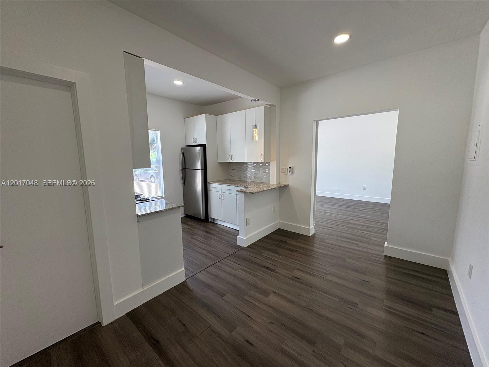3237 Southwest 4th Street, Unit 6 Miami, FL 33135 - Photo 5 of 10 an empty room with wooden floor and a kitchen