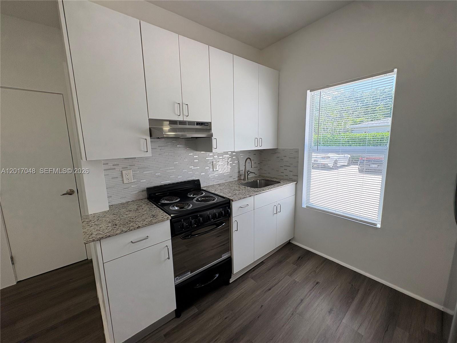 3237 Southwest 4th Street, Unit 6 Miami, FL 33135 - Photo 7 of 10 a kitchen with granite countertop white cabinets and white appliances