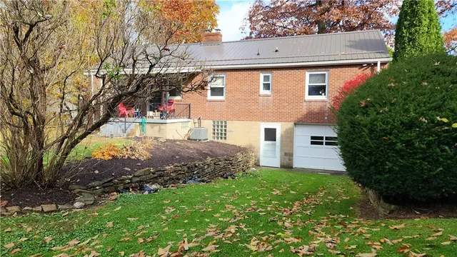 a view of a house with a small yard and a large tree