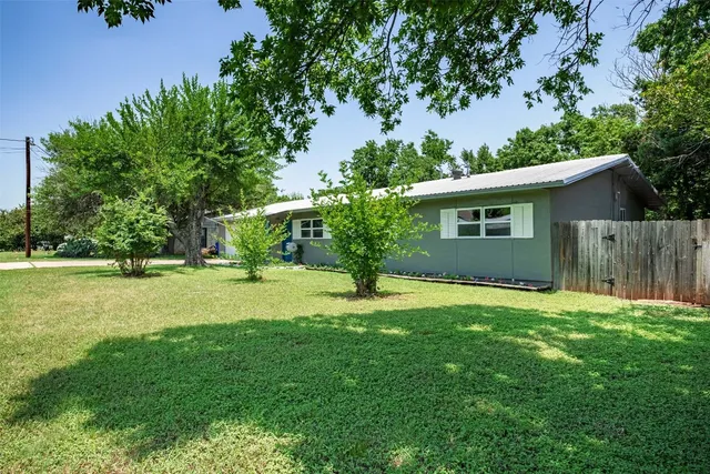 a backyard of a house with plants and large tree