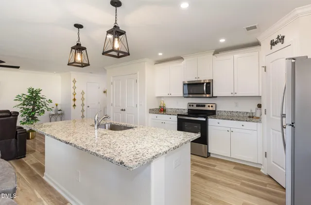 a kitchen with stainless steel appliances granite countertop a sink a stove a refrigerator and cabinets