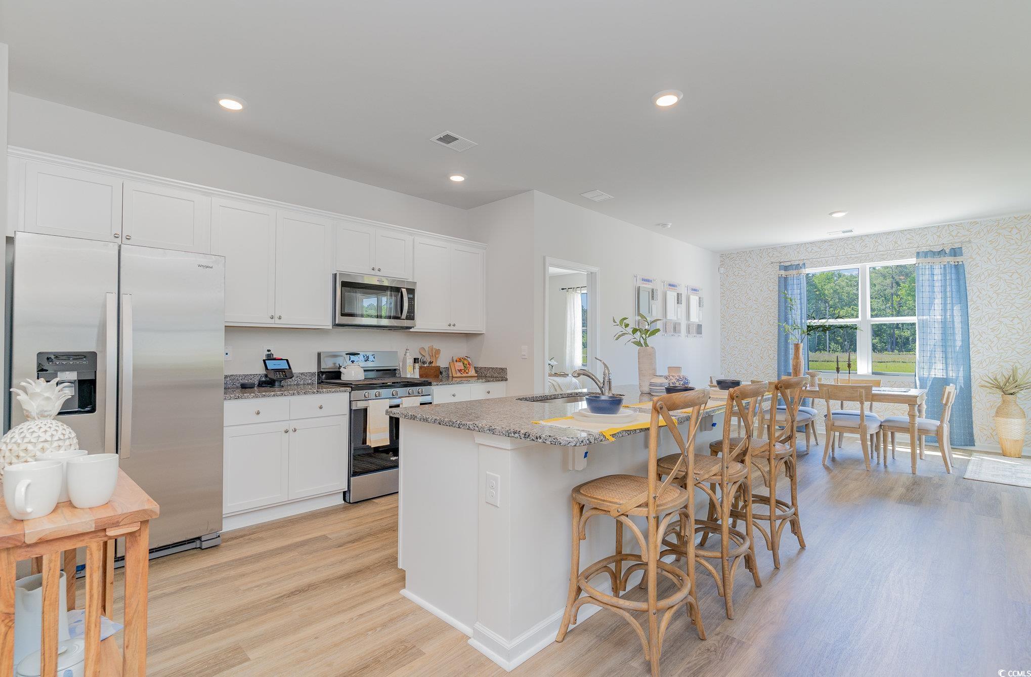 7366 Meadow Walk Loop Loris, SC 29569 - Photo 10 of 20 Kitchen featuring stainless steel appliances, light wood-style flooring, an island with sink, white cabinets, and recessed lighting