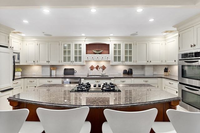 a kitchen with stainless steel appliances granite countertop a stove a sink dishwasher and white cabinets with wooden floor
