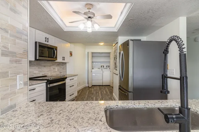 a kitchen with stainless steel appliances kitchen island granite countertop a refrigerator a sink a stove with cabinets