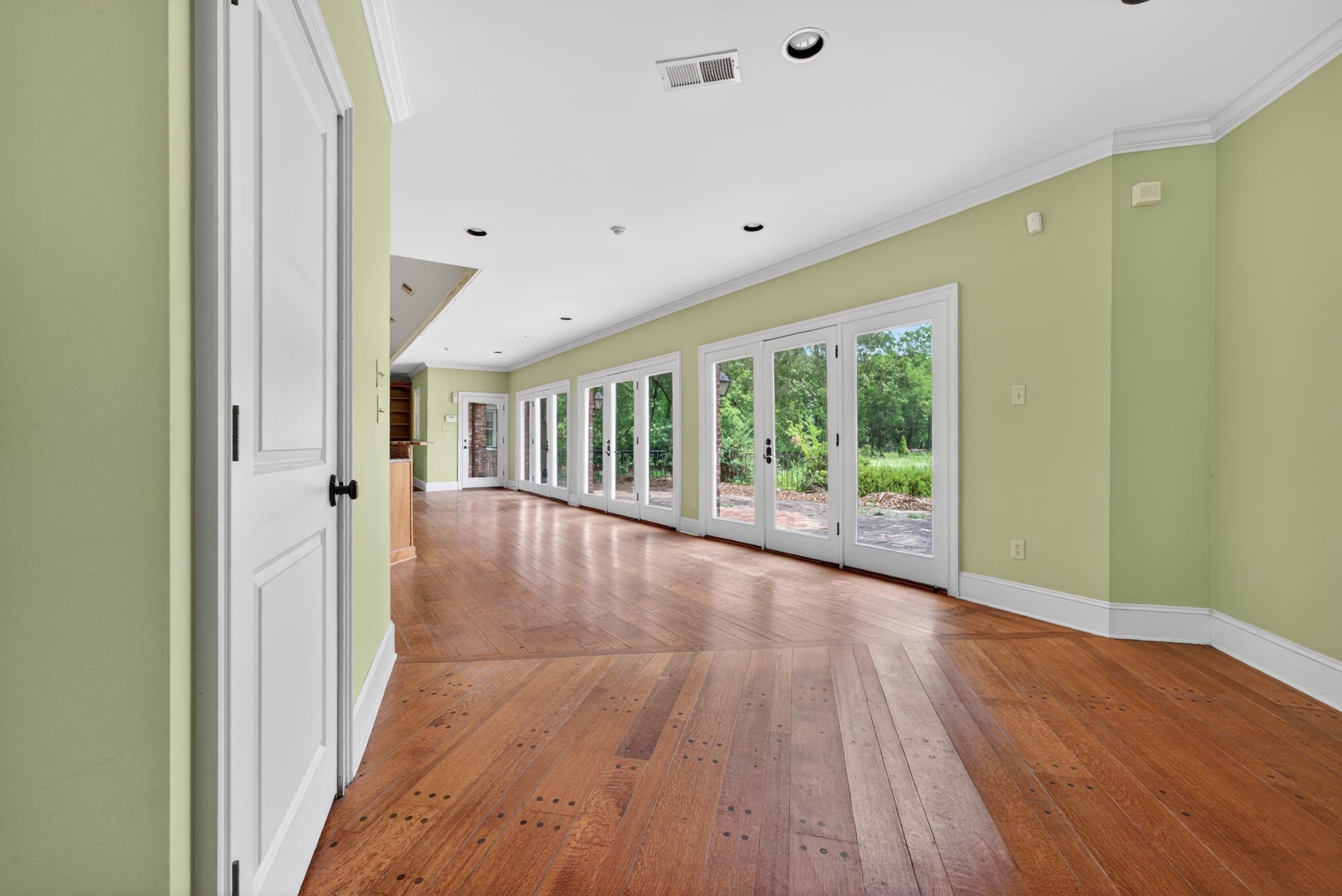 530 West Raines Road Memphis, TN 38109 - Photo 17 of 38 Spacious room featuring wood flooring, a full wall of French doors, recessed lighting, crown molding, and light green painted walls