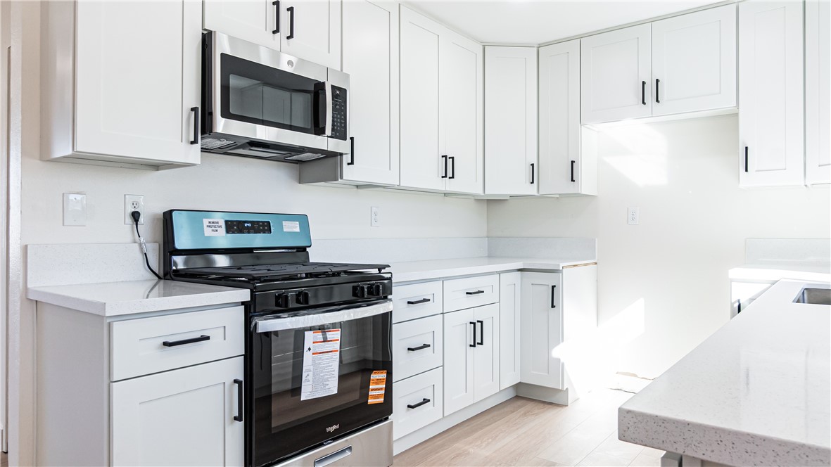 9293 Guava Avenue Hesperia, CA 92345 - Photo 6 of 32 a kitchen with stainless steel appliances granite countertop white cabinets a sink a stove a microwave and dishwasher