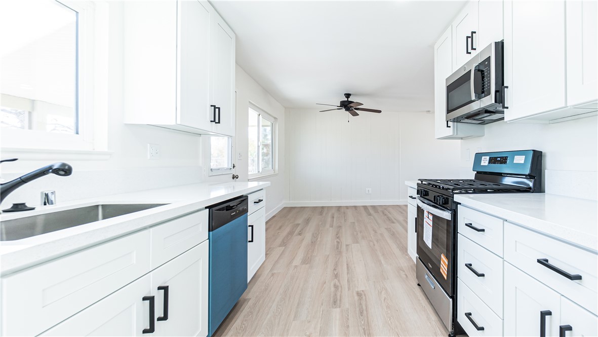 9293 Guava Avenue Hesperia, CA 92345 - Photo 8 of 32 a kitchen with stainless steel appliances granite countertop a sink dishwasher stove and white cabinets with wooden floor