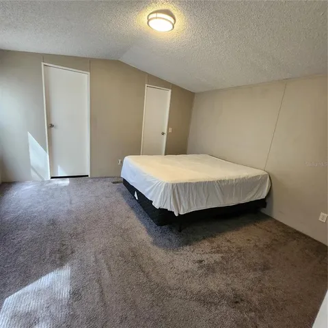 a spacious bedroom with a bed and cabinet