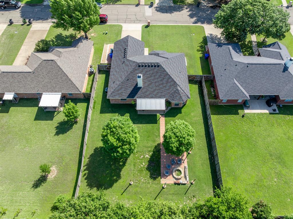 10512 Whitney Trace Drive Waco, TX 76708 - Photo 17 of 39 Expansive backyard featuring a manicured lawn, established trees, and a brick paver patio with a built-in fire pit