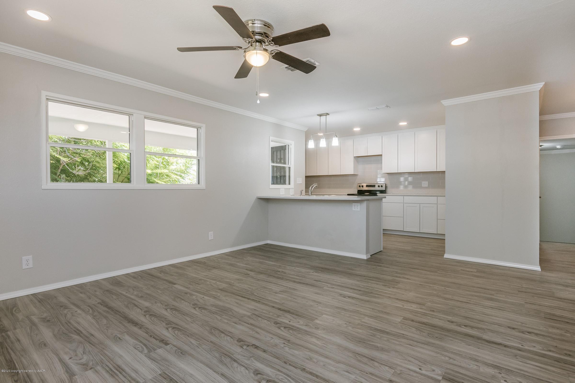 5135 Bowie Street Amarillo, TX 79110 - Photo 2 of 24 an empty room with wooden floor a kitchen view and a window