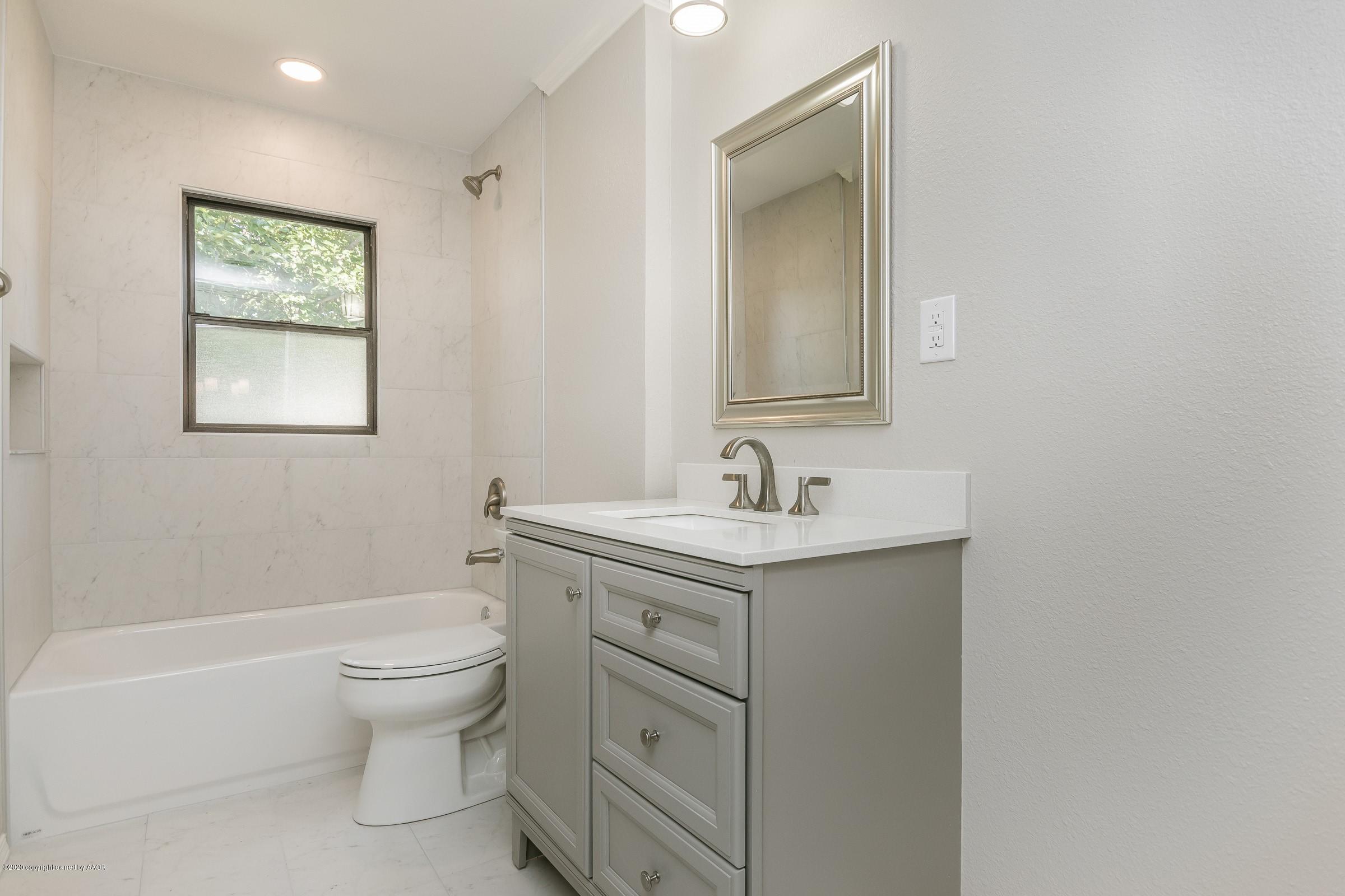 5135 Bowie Street Amarillo, TX 79110 - Photo 19 of 24 a bathroom with a granite countertop toilet a sink and a mirror
