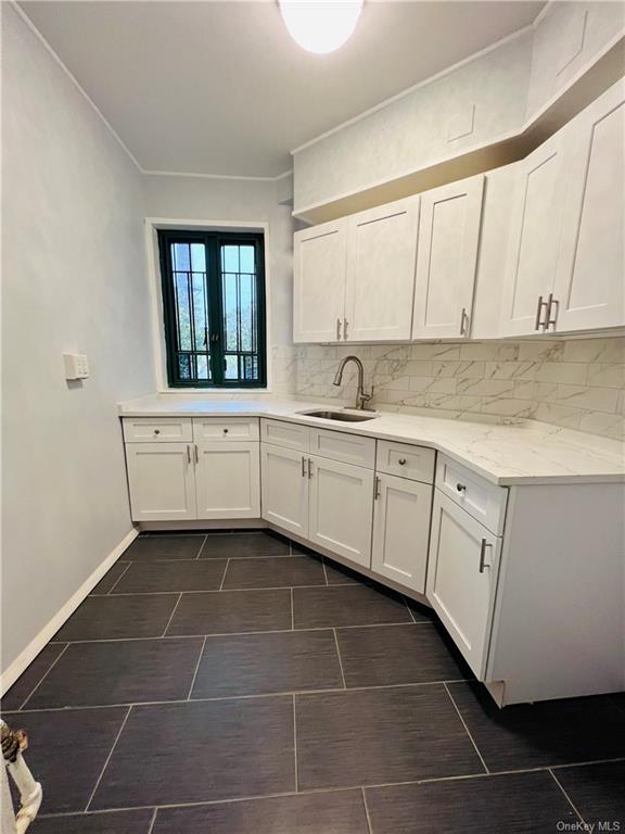 a kitchen with a sink dishwasher and white cabinets with wooden floor