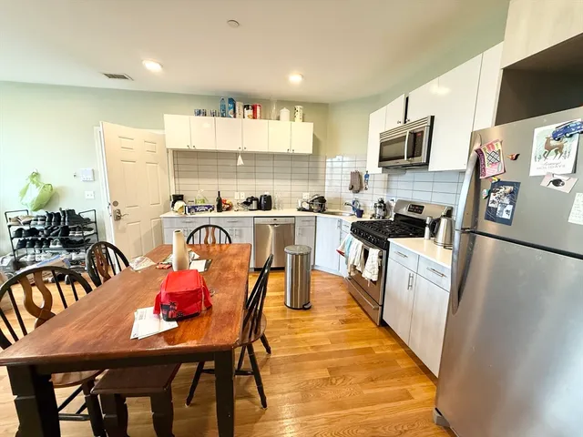 a kitchen with stainless steel appliances granite countertop a stove top oven a sink a dining table and chairs