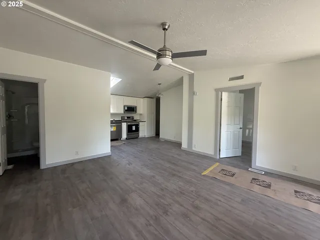 a view of empty room with wooden floor and ceiling fan