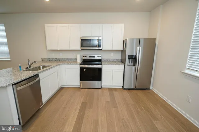 a kitchen with a sink a refrigerator a microwave and cabinets