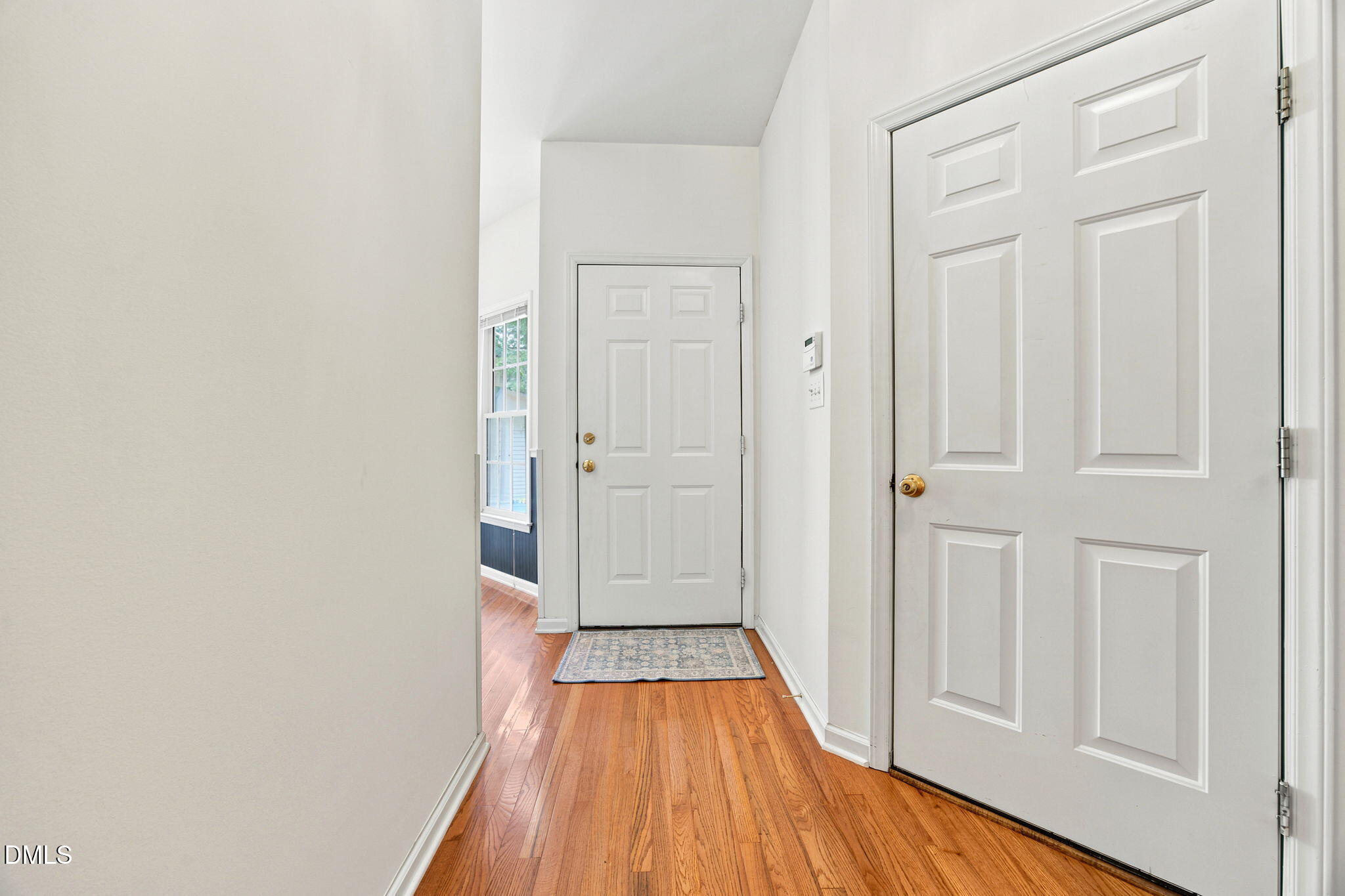 8211 Hempshire Place, Unit 104 Raleigh, NC 27613 - Photo 29 of 34 Entryway featuring wood-finish flooring, white paneled doors, and natural light from a window