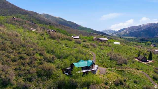 6 Beaver Springs Rancheros Oakley, UT 84055 - Photo 59 of 68 Hillside property featuring a green metal roof, a wrap-around deck, and a gravel driveway