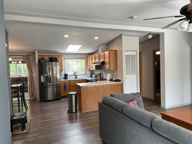 a living room with stainless steel appliances furniture refrigerator and kitchen view