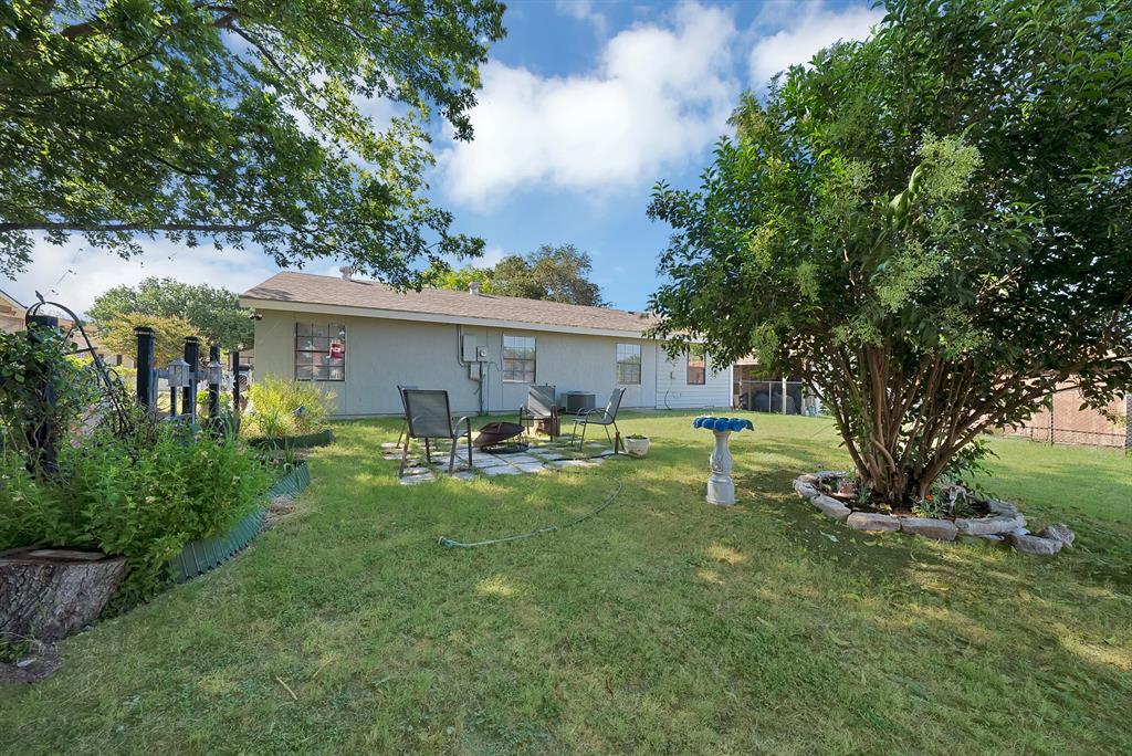 9519 County View Road Dallas, TX 75249 - Photo 23 of 31 Spacious backyard featuring a manicured lawn, established trees, and a stone-paved patio area