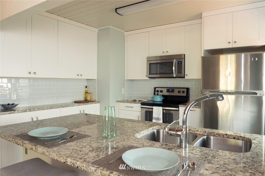 736 North 88th Street Seattle, WA 98103 - Photo 14 of 17 a kitchen with granite countertop a sink a stove and a microwave