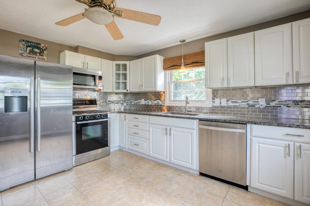 159 Fair Oak Road Springfield, MA 01128 - Photo 6 of 21 a kitchen with granite countertop a refrigerator oven a sink and white cabinets