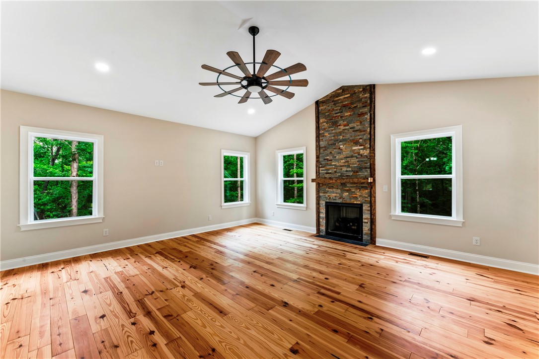 110 Gabriel Way Pickens, SC 29671 - Photo 12 of 48 A spacious great room showcases gleaming hardwood floors and a striking stone fireplace under a vaulted ceiling.