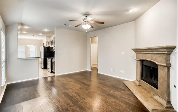 a view of an empty room with kitchen and a fireplace