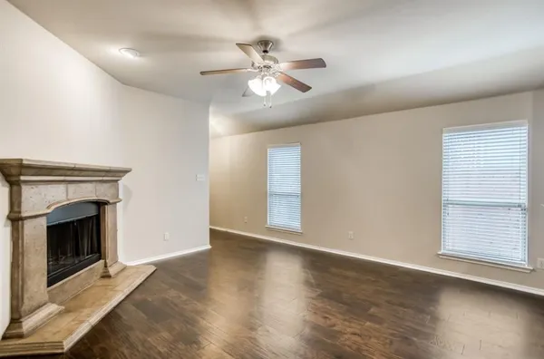a view of an empty room with wooden floor and a fireplace