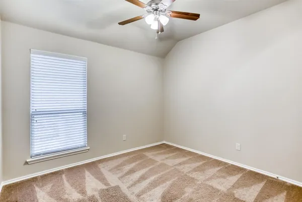 an empty room with a chandelier fan and windows