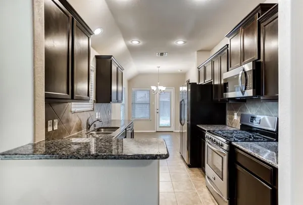 a kitchen with stainless steel appliances granite countertop a sink a stove and a refrigerator