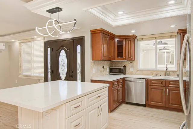 a kitchen with stainless steel appliances a sink a stove a refrigerator cabinets and a dining table