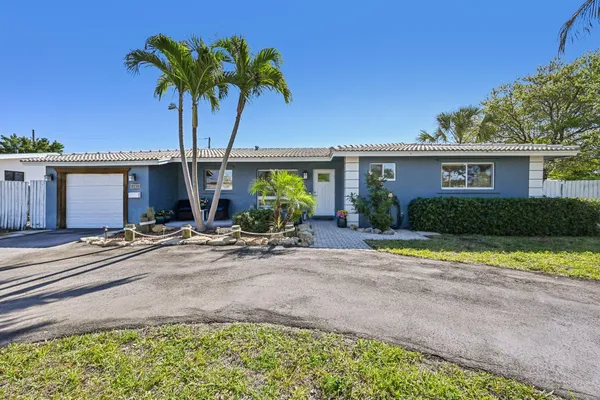 front view of a house with a yard and palm trees