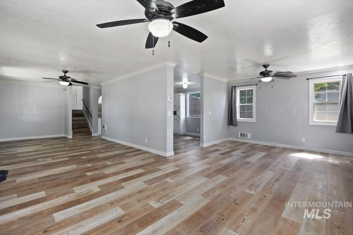 1940 Q Street Heyburn, ID 83336 - Photo 4 of 30 Spacious interior featuring wood-finish flooring, light gray walls, and multiple ceiling fans