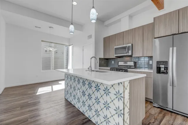 a kitchen with stainless steel appliances granite countertop a sink a stove a refrigerator cabinets and wooden floor