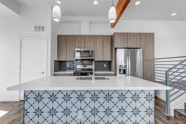 a kitchen with stainless steel appliances a sink a stove a refrigerator cabinets and a counter top space