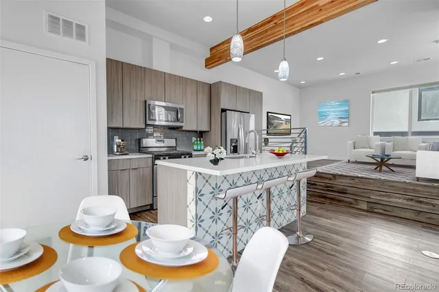 a kitchen with stainless steel appliances granite countertop a white cabinets and chairs