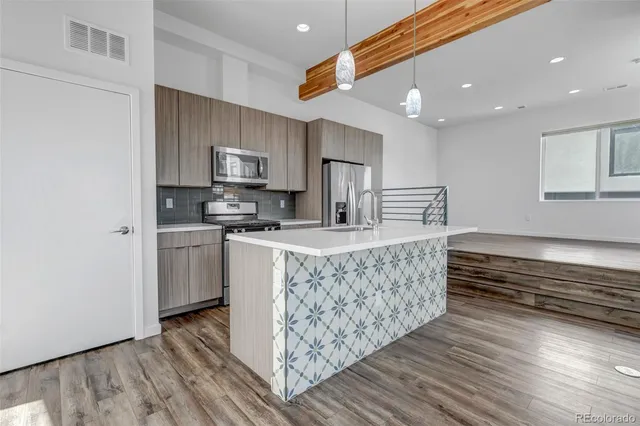 a kitchen with stainless steel appliances granite countertop a stove a sink dishwasher and a refrigerator with wooden floor