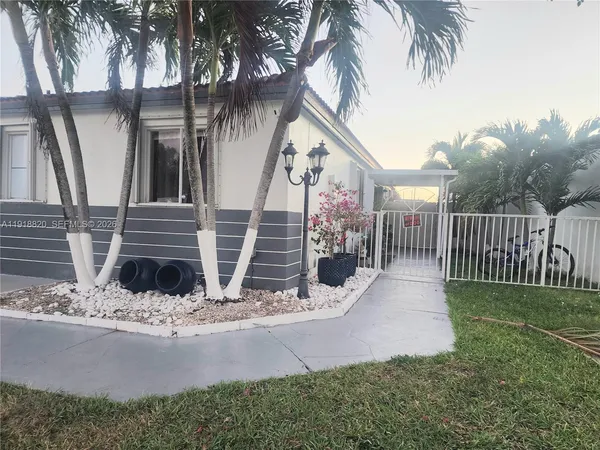 a view of a house with a yard and potted plants