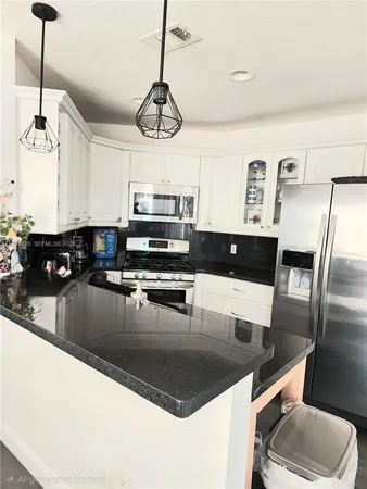 a kitchen with stainless steel appliances granite countertop a sink a stove a microwave a refrigerator a stove and white cabinets