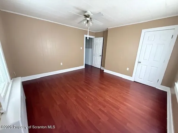 an empty room with wooden floor ceiling fan and windows
