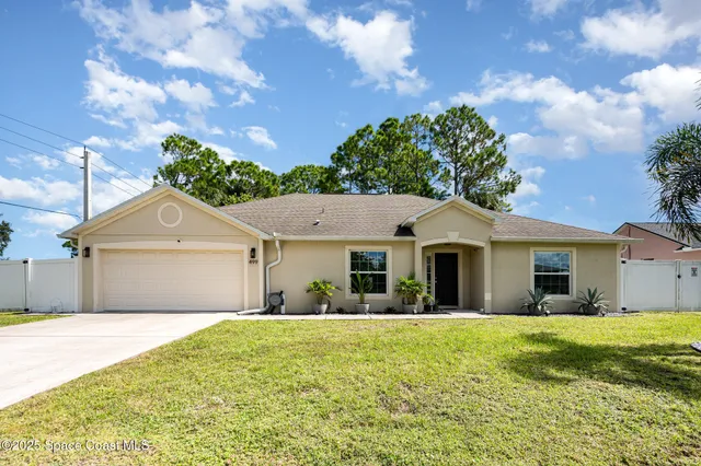 a front view of a house with a yard and potted plants