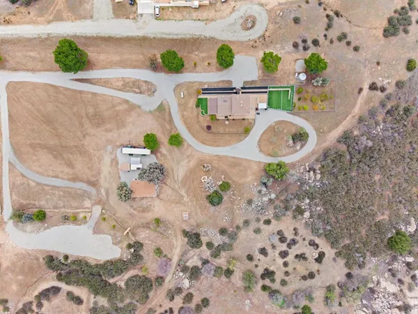 an aerial view of residential houses with outdoor space and trees