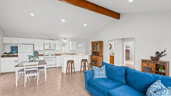 a living room with furniture a dining table and chairs kitchen view with wooden floor