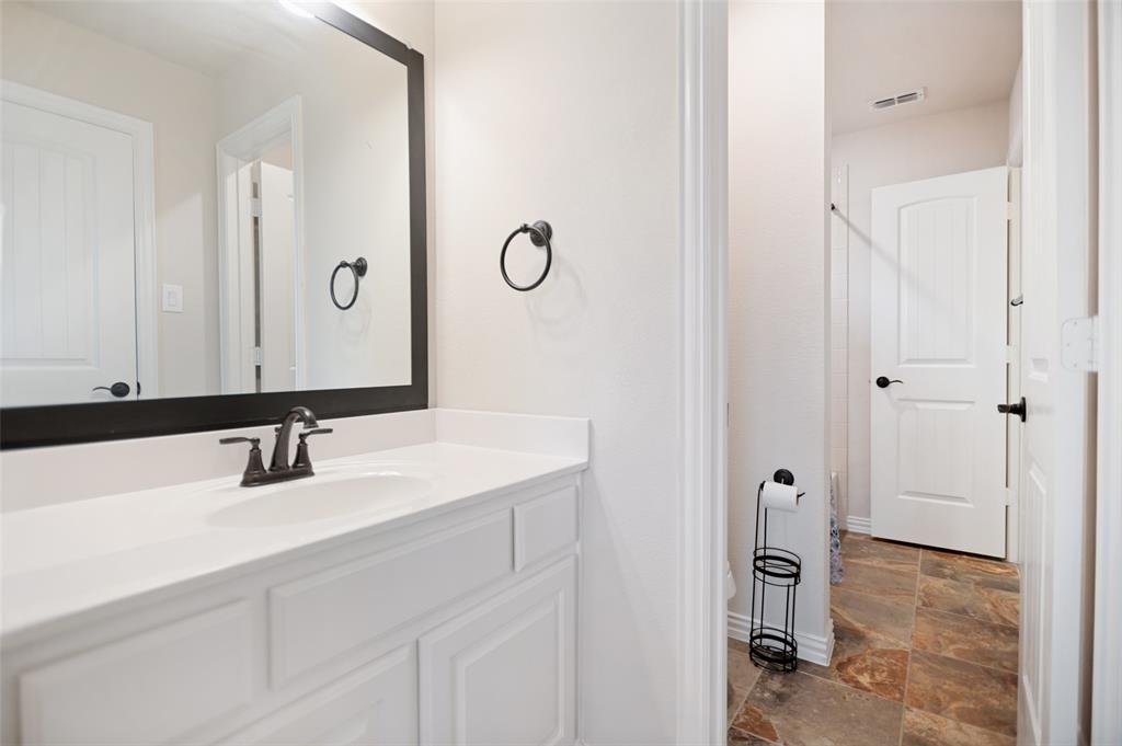 413 Frontier Court Midlothian, TX 76065 - Photo 22 of 26 Bathroom vanity featuring a white countertop, an undermount sink, and a dark bronze two-handle faucet