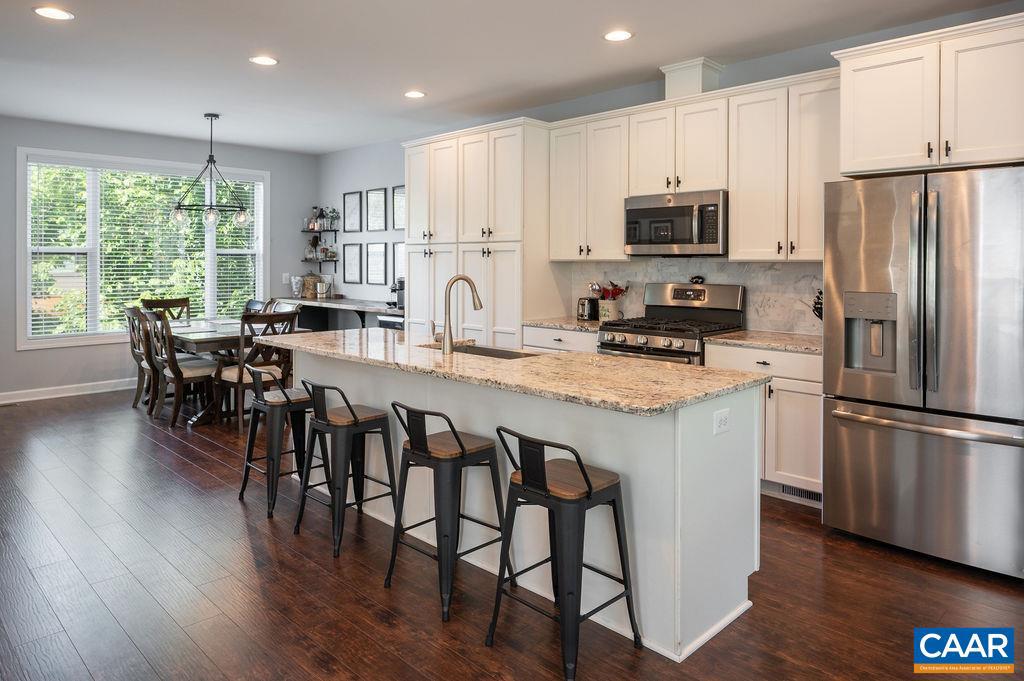 148 Junction Lane Charlottesville, VA 22902 - Photo 4 of 29 a kitchen with stainless steel appliances granite countertop a refrigerator a stove a microwave a dining table and chairs with wooden floor