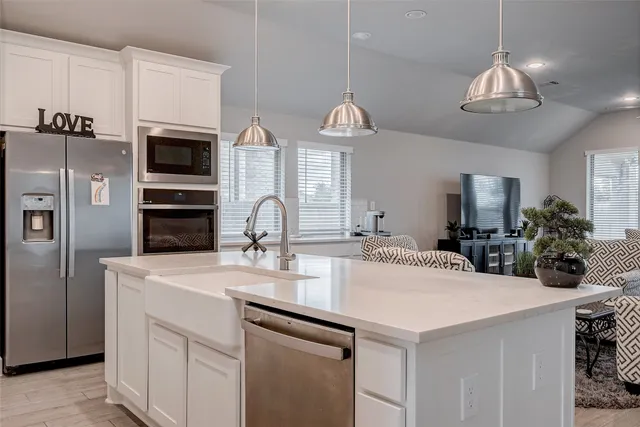 a kitchen with stainless steel appliances a sink a chandelier and wooden floor