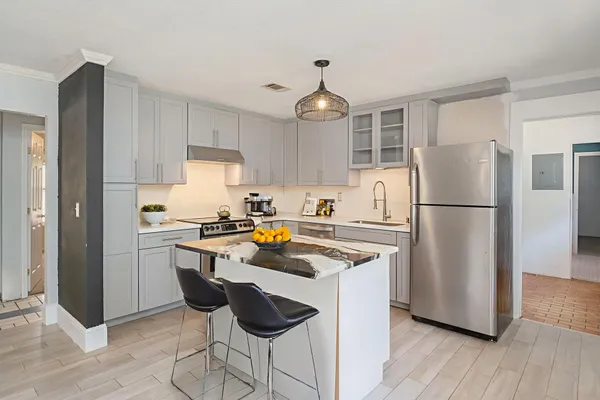 a kitchen with stainless steel appliances granite countertop a refrigerator a sink dishwasher a stove and white cabinets with wooden floor
